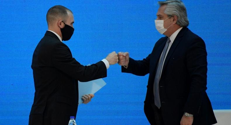 Argentina's President Alberto Fernandez (R) and Economy Minister Martin Guzman greet each other with a fist bump after announcing the restructuring of a $66 billion foreign-law debt