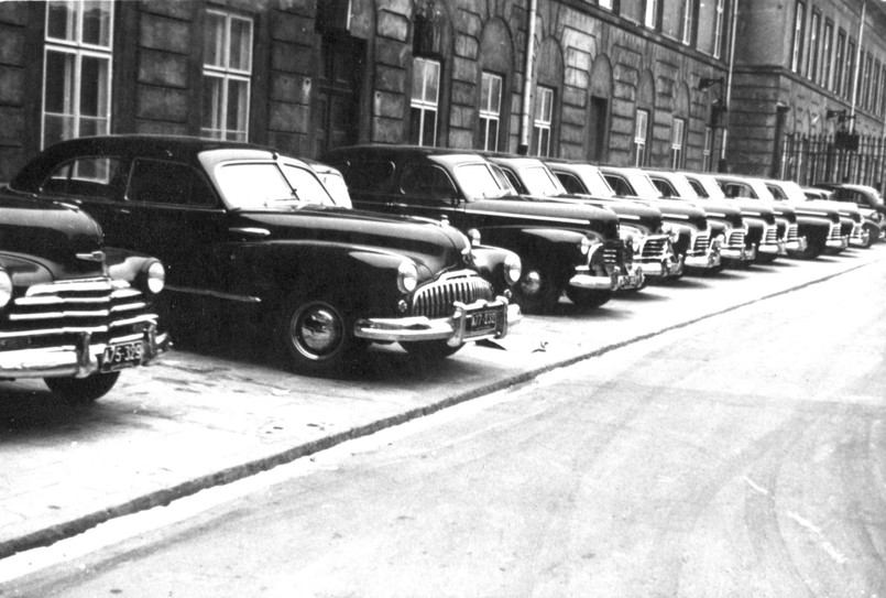 Koniec lat 40. przed jednym z ministerstw w Warszawie. Pierwszy od lewej (widać tylko przód) Chevrolet z 1947 roku, dalej Buick, a następnie rząd 8 Chevroletów