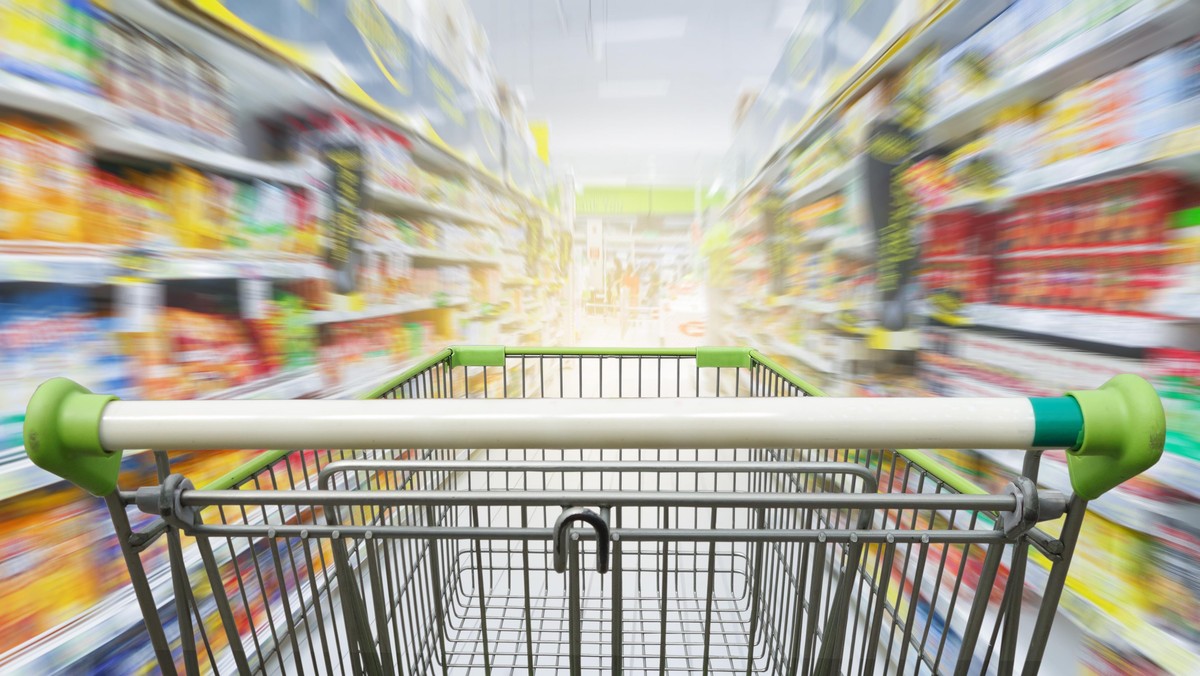 Supermarket aisle with empty green shopping cart