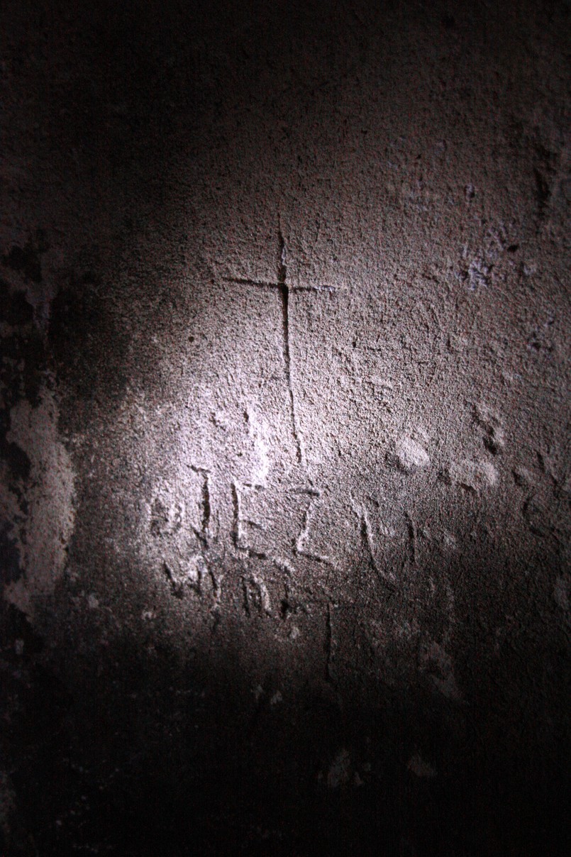 Wyryty w karcerze krzyż i napis "Jezu wyratuj". W piwnicach domu przy ulicy Świerszcza są dwa takie pomieszczenia. Ciasne, wąskie, pozbawione dostępu światła, z opadającym sufitem. W pozycji wyprostowanej można stanąć w nich tylko przy drzwiach