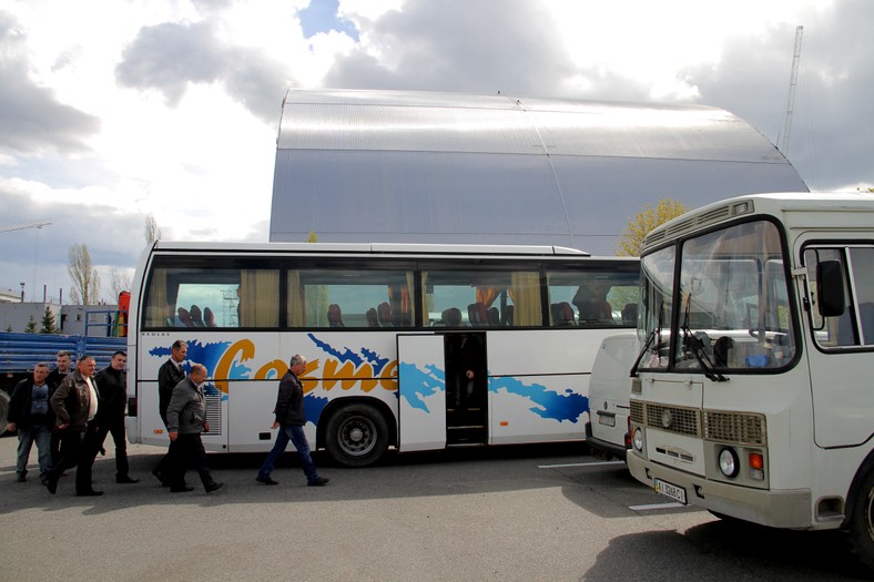 Autobusy na parkingu pod elektrownią. W tle widoczny nowy sarkofag