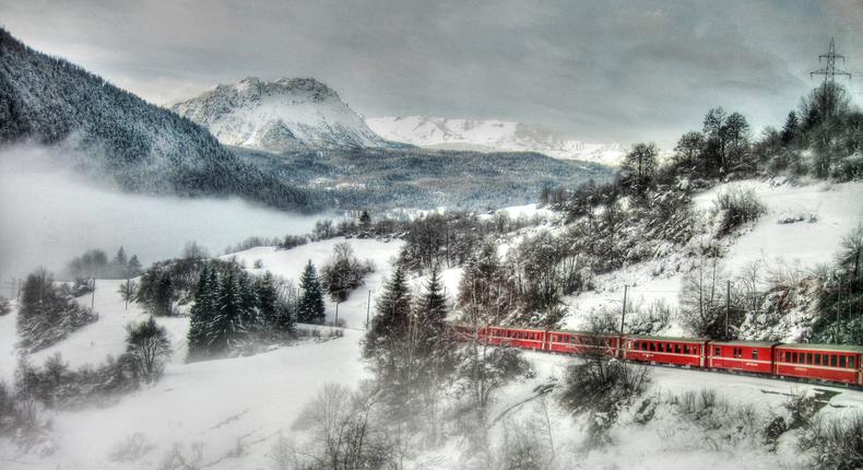 Switzerland's Glacier Express surrounded by snowy mountains and trees.Arthur Mallett/Getty Images