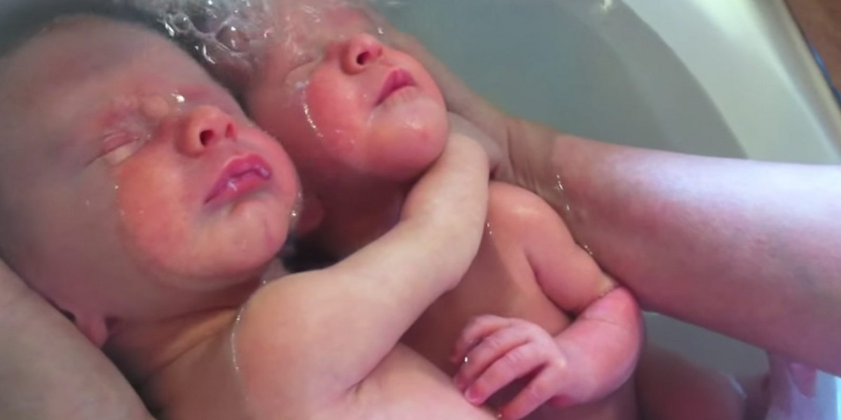 Bliźniaki po urodzeniu przytulają się w kąpieli.
