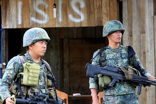 Soldiers stand guard along the main street of Mapandi village as government troops continue their as