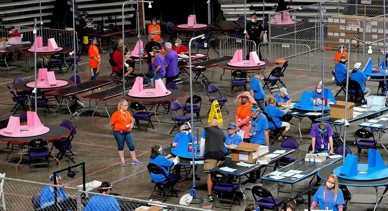 In this May 6, 2021, file photo, Maricopa County ballots cast in the 2020 general election are examined and recounted by contractors working for Florida-based company, Cyber Ninjas at Veterans Memorial Coliseum in Phoenix. Arizonas largest county has approved nearly $3 million for new vote-counting machines to replace those given to legislative Republicans for a partisan review of the 2020 election. The GOP-controlled Maricopa County Board of Supervisors said Wednesday, July 14, 2021 that the machines were compromised because they were in the control of firms not accredited to handle election equipment.
