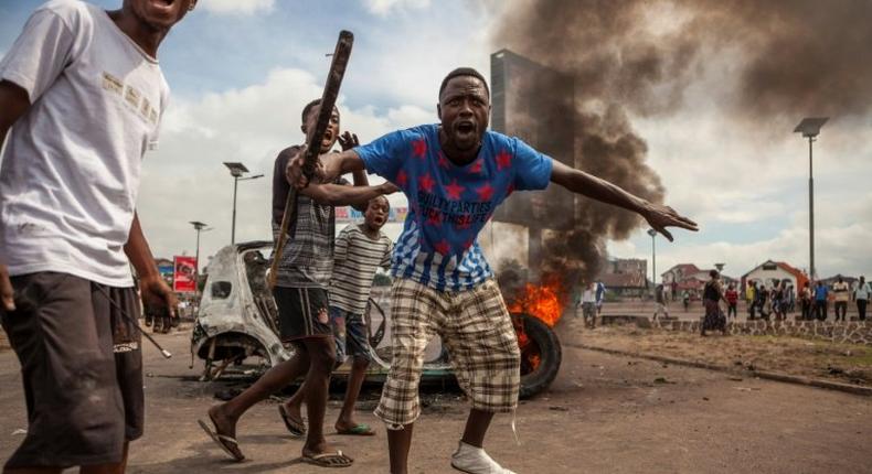 Demonstrators gather in front of a burning car during an opposition rally in Kinshasa