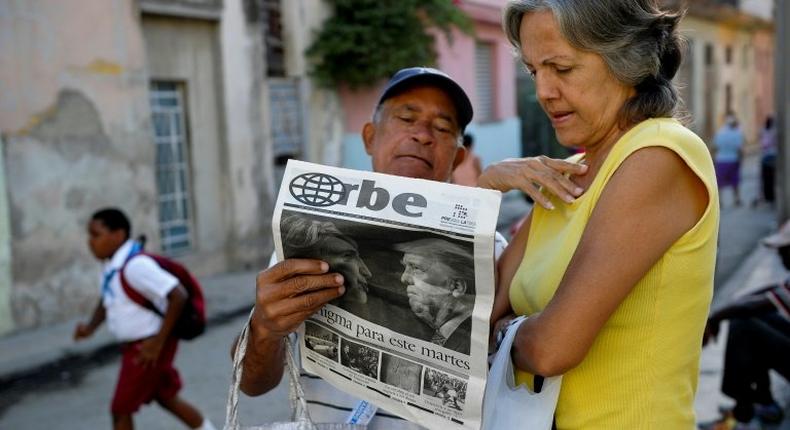 Cubans read a newspaper with its front page informing of the victory of US presidential candidate Donal Trump in a street of Havana, on November 9, 2016