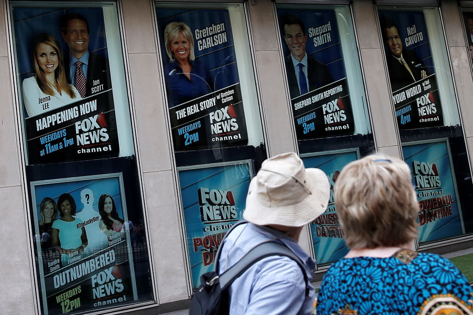 People walk by posters of Fox News personalities including Gretchen Carlson.