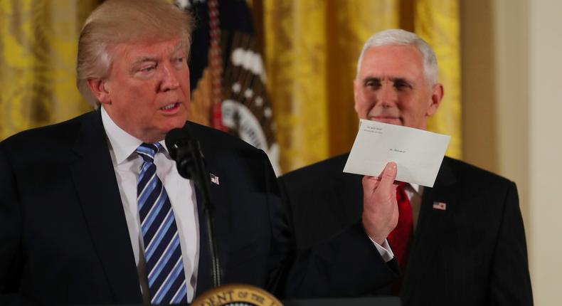 President Donald Trump, flanked by Vice President Mike Pence, addresses staff at the White House.