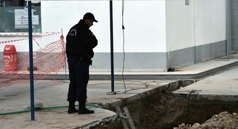 A policeman looks into a hole in Thessaloniki, northern Greece where an unexploded World War II bomb was found during work to expand a petrol station's underground tanks on February 8, 2017