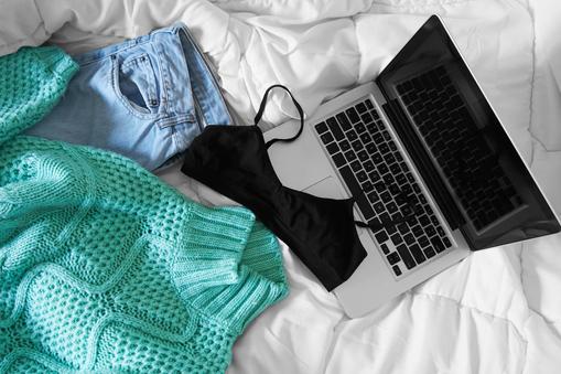 Female outfit and laptop laid out on bed, morning light
