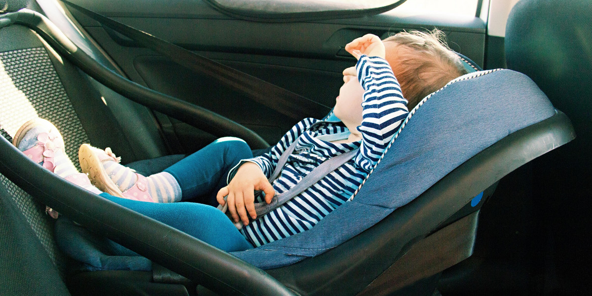 baby smile in a safety car seat. security. one year old child girl in blue wear sit on auto cradle. Rules for the Safe Transport of Children. Holders