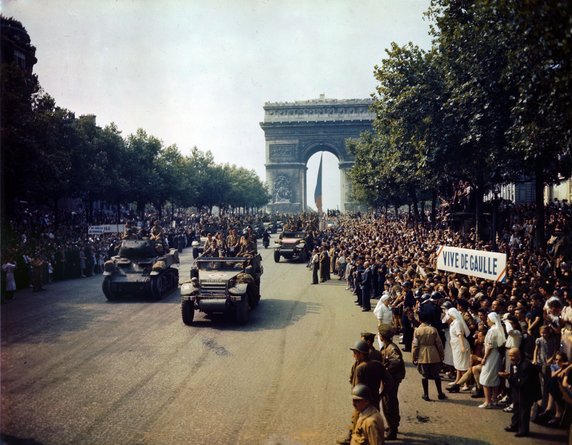 Parada zwycięstwa na Polach Elizejskich po wyzwoleniu Paryża. Napis po prawej głosi „Niech żyje de Gaulle” (26 sierpnia 1944, domena publiczna).