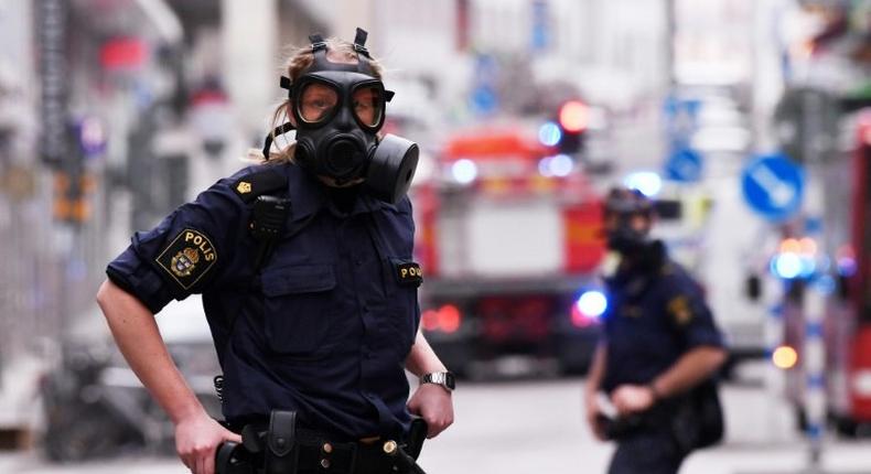 Police officers wearing gas masks on duty at the scene of a truck attack in central Stockholm on April 7, 2017