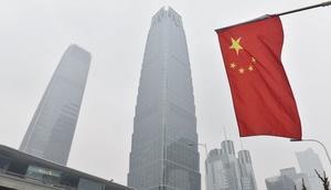 A Chinese flag flies near buildings in the central business district on a polluted day in Beijing on February 27, 2018.GREG BAKER via Getty Images