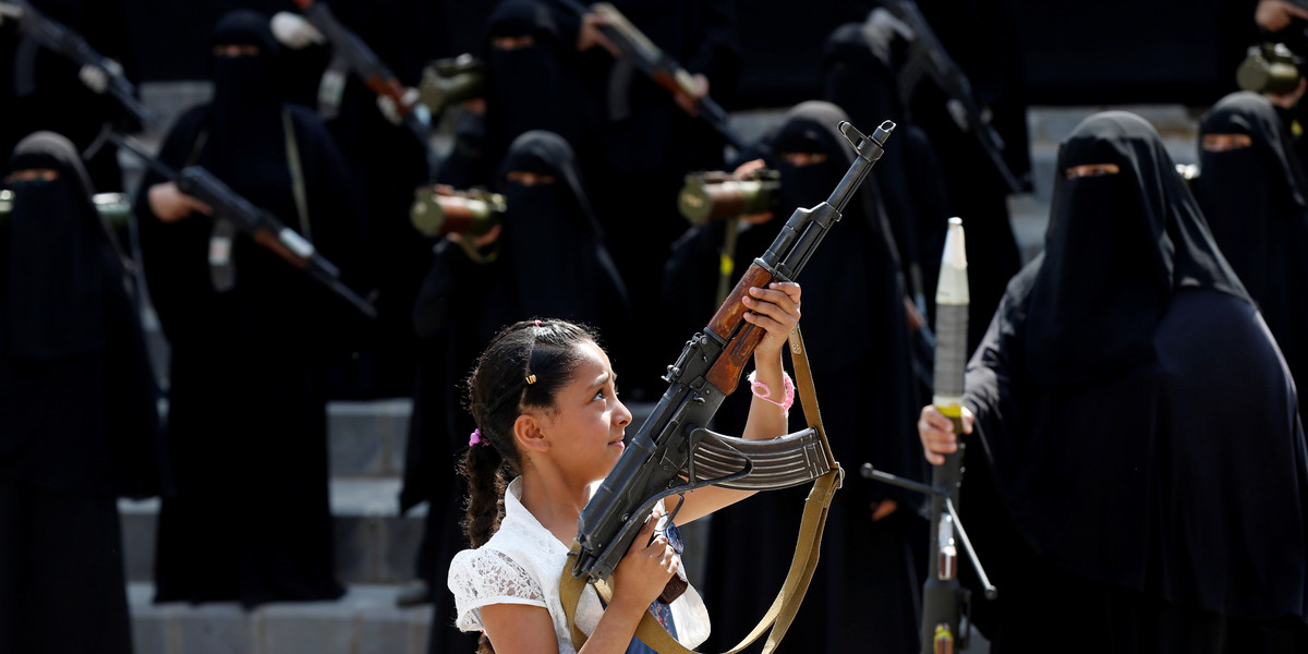 A girl holds a rifle in front of women loyal to the Houthi movement taking part in a parade to show support to the movement in Sanaa, Yemen September 6, 2016.