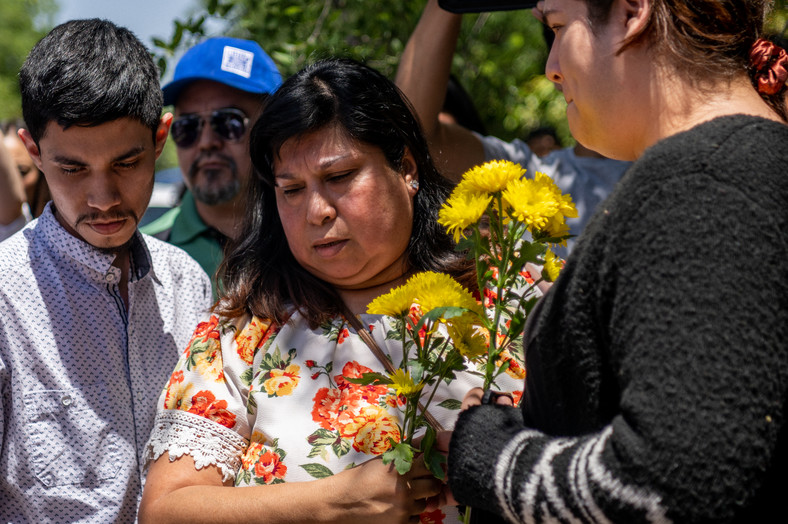 Rodziny składające kwiaty przed podstawówką w Uvalde, gdzie doszło do strzelaniny.