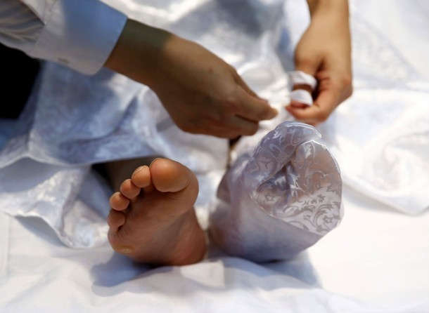 A funeral undertaker puts a traditional sock on the foot of a model during an encoffinment competiti