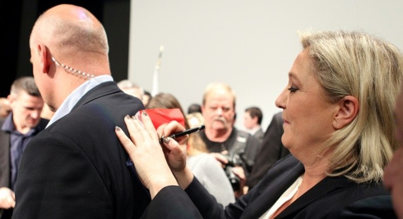 National Front (FN) leader Marine Le Pen (R) signs autographs on her bodyguard's back during a 2015 campaign rally in Corsica