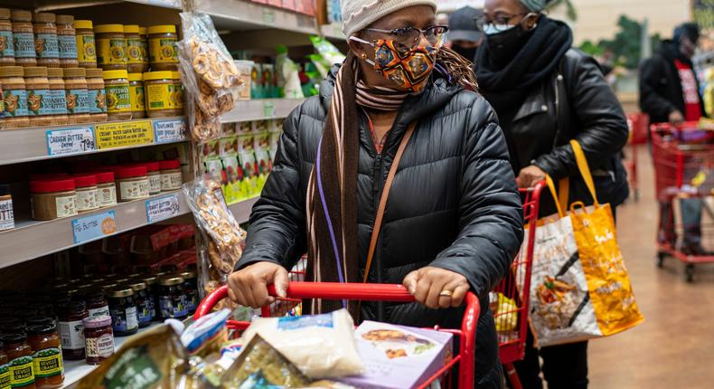 A woman wearing a mask moves her shopping cart December 3, 2020 in a Trader Joe's supermarket in New York City.
