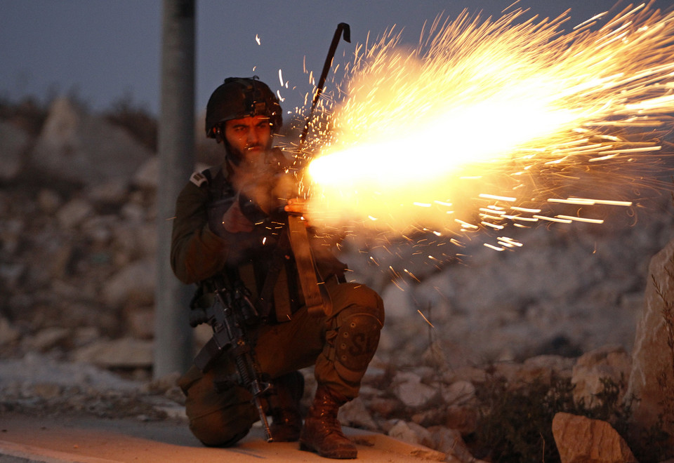 An Israeli soldier fires tear gas towards Palestinian youths throwing stones near Bethlehem