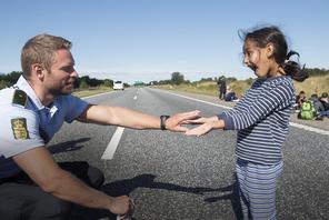 A Danish policeman plays with a migrant girl at the E45 freeway north of Padborg