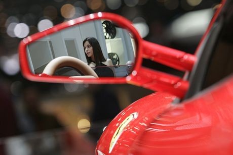 A model is reflected in a mirror of a Ferrari F430 Spider on display during the first media day of the 77th Geneva car show at the Palexpo in Geneva March 6, 2007. REUTERS/Stefan Wermuth (SWITZERLAND)