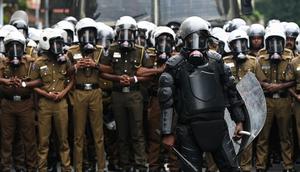Policemen stand guard as university students and demonstrators protest in Colombo against the Sri Lankan government.
