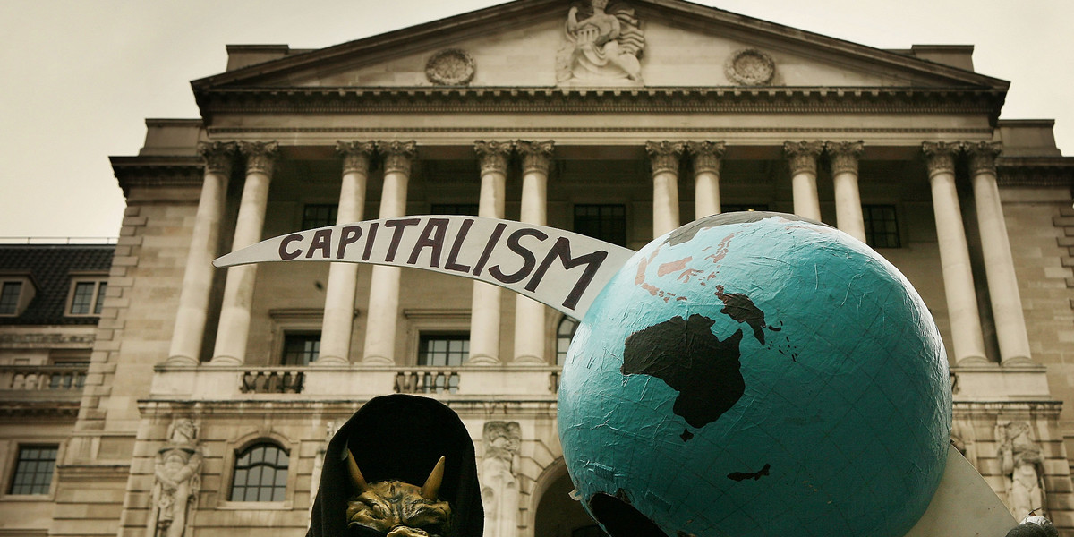 A grim reaper figure holds a globe pierced by the scythe of capitalism in front of the Bank of England during a protest on October 13, 2008 in London