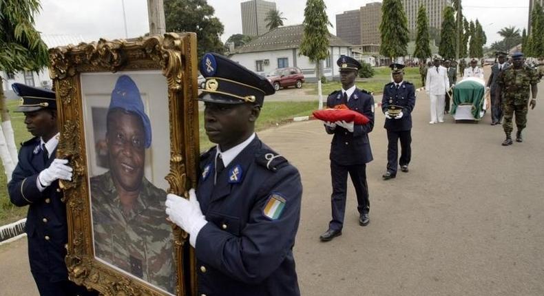 Ivory Coast soldiers carry the portrait and coffin of Robert Guei, former president and army general, during a funeral procession held at the Ivorian Army Chief of Staff headquarters in Abidjan in a file photo. REUTERS/Thierry Gouegnon