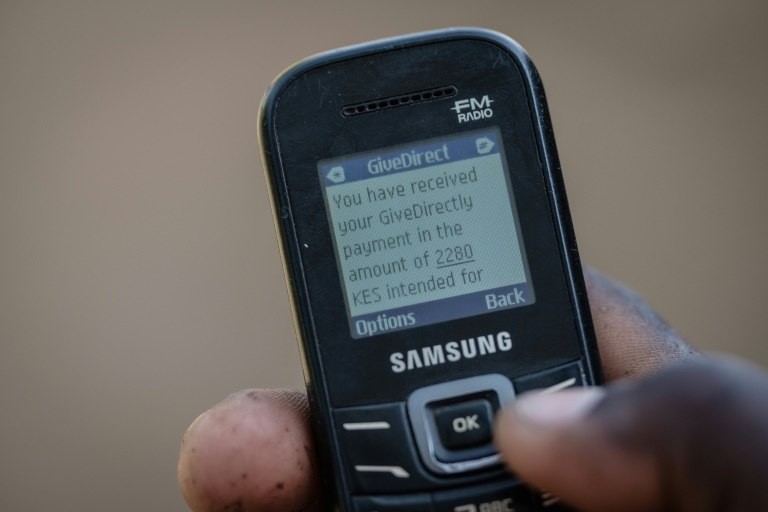 A villager shows his mobile phone's monitor displaying a message confirming the universal basic income transaction, 2,250 shillings per month ($22,19 euros)