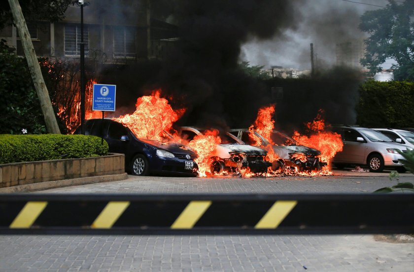 A policeman runs past burning cars at the scene where explosions and gunshots were heard at the Dusi