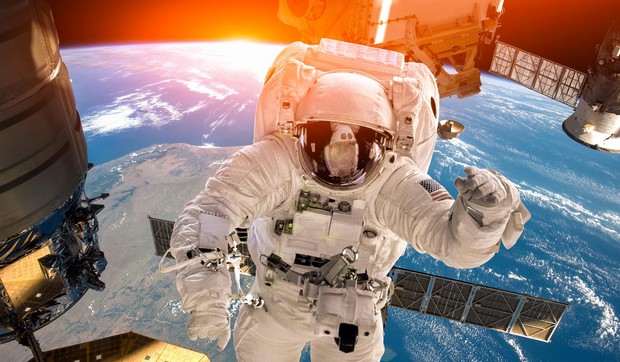 Ilustracija: Međunarodna svemirska stanica i astronaut u svemiru iznad planete Zemlje