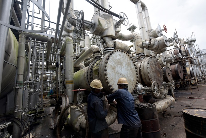 A picture taken on September 16, 2015 shows workers trying to tie a pipe of the first refinery in Nigeria, which was built in 1965 in oil rich Port Harcourt, Rivers State. [PIUS UTOMI EKPEI/AFP via Getty Images]