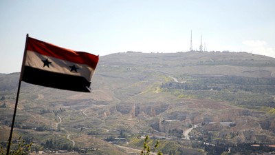 A Syrian national flag flutters as Qasioun mountain is seen in the background from Damascus