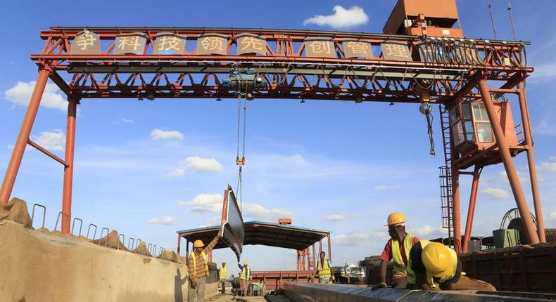 Workers are seen near a sign written in Chinese at the construction site of the Mombasa-Nairobi standard gauge railway (SGR) at Emali in Kenya October 10, 2015. Picture taken October 10, 2015. REUTERS/Noor Khamis
