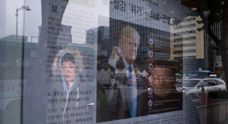 A man looks at a newspaper displaying an image of Donald Trump and coverage of the US presidential elections, in Seoul