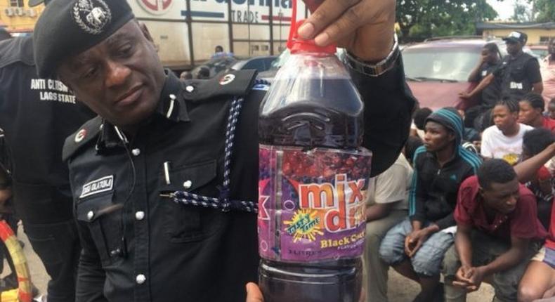 An illustrative photo of a police officer displaying a bottle containing skuchies drink. [gpowerradio]