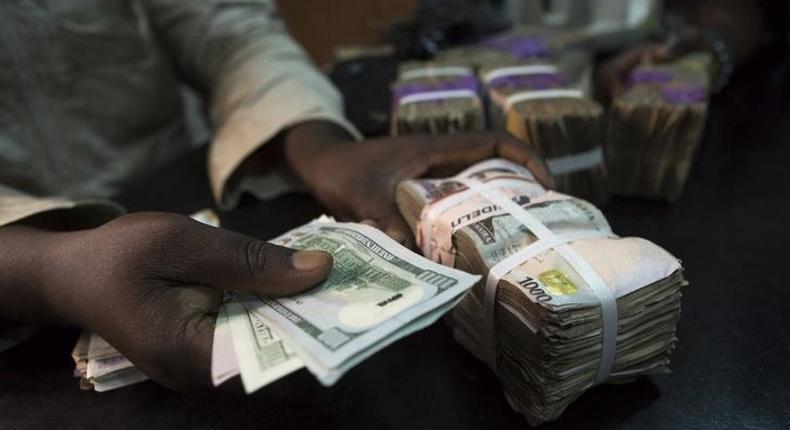 A trader changes dollars with naira at a currency exchange store in Lagos February 12, 2015 [REUTERS/Joe Penney]
