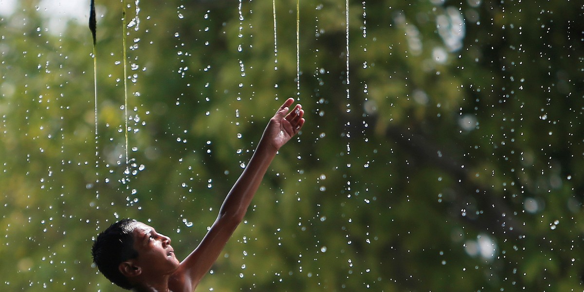 A boy cools off under a water fountain on a hot summer day in New Delhi, India.