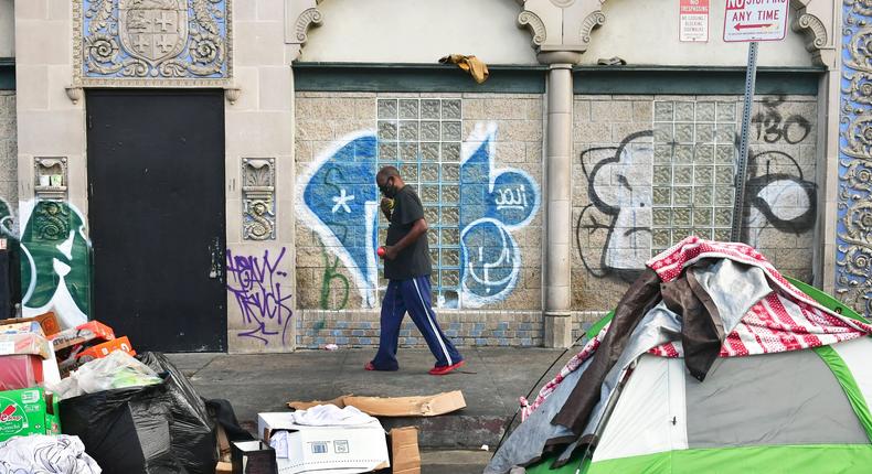 A man walks past tents housing the homeless on the streets in the Skid Row community of Los Angeles, California.