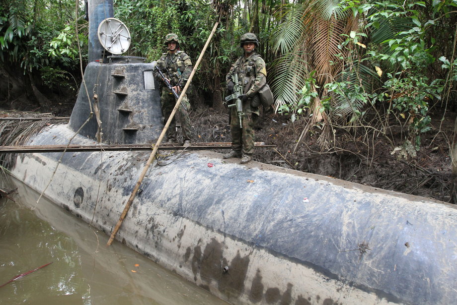 Members of the Colombian navy stand guard on a seized submarine built by drug smugglers in a makeshift shipyard in Timbiqui, Cauca department. Colombian authorities said the submersible craft was to be used to transport 8 tons of cocaine into Mexico.