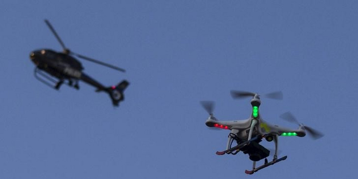 A police helicopter flies past a UAV drone Quadcopter over west Baltimore, Maryland, May 2, 2015.