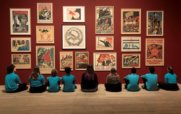 School children pose in front of a wall of Soviet Union propaganda posters at the Red Star Over Russ