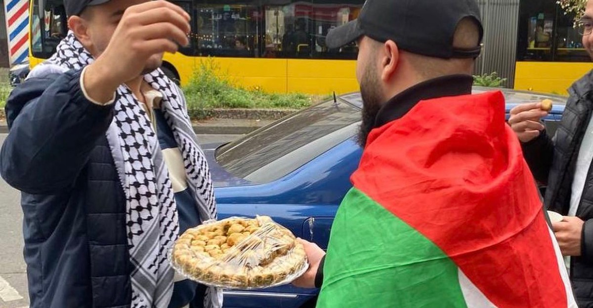 Mężczyzna z palestyńską flagą rozdaj słodycze na jednej z ulic Berlina