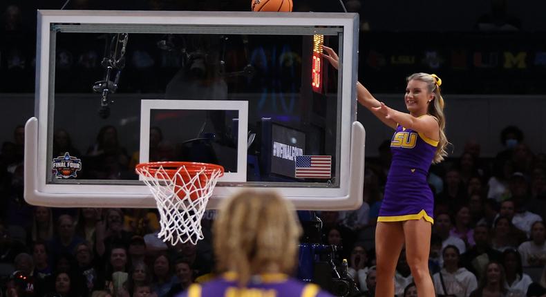 An LSU cheerleader uses a stunt to grab a game ball stuck above the backboard.Maddie Meyer/Getty Images