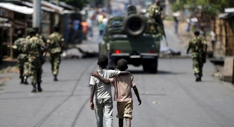 Boys walk behind patrolling soldiers in Bujumbura, Burundi, May 15, 2015 REUTERS/Goran Tomasevic