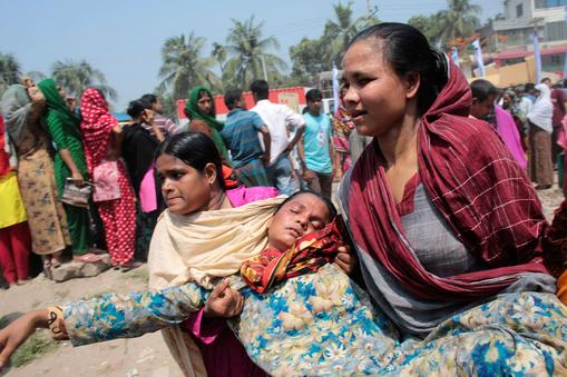 Women help a relative of a garment worker, who went missing in the Rana Plaza collapse, after she fa