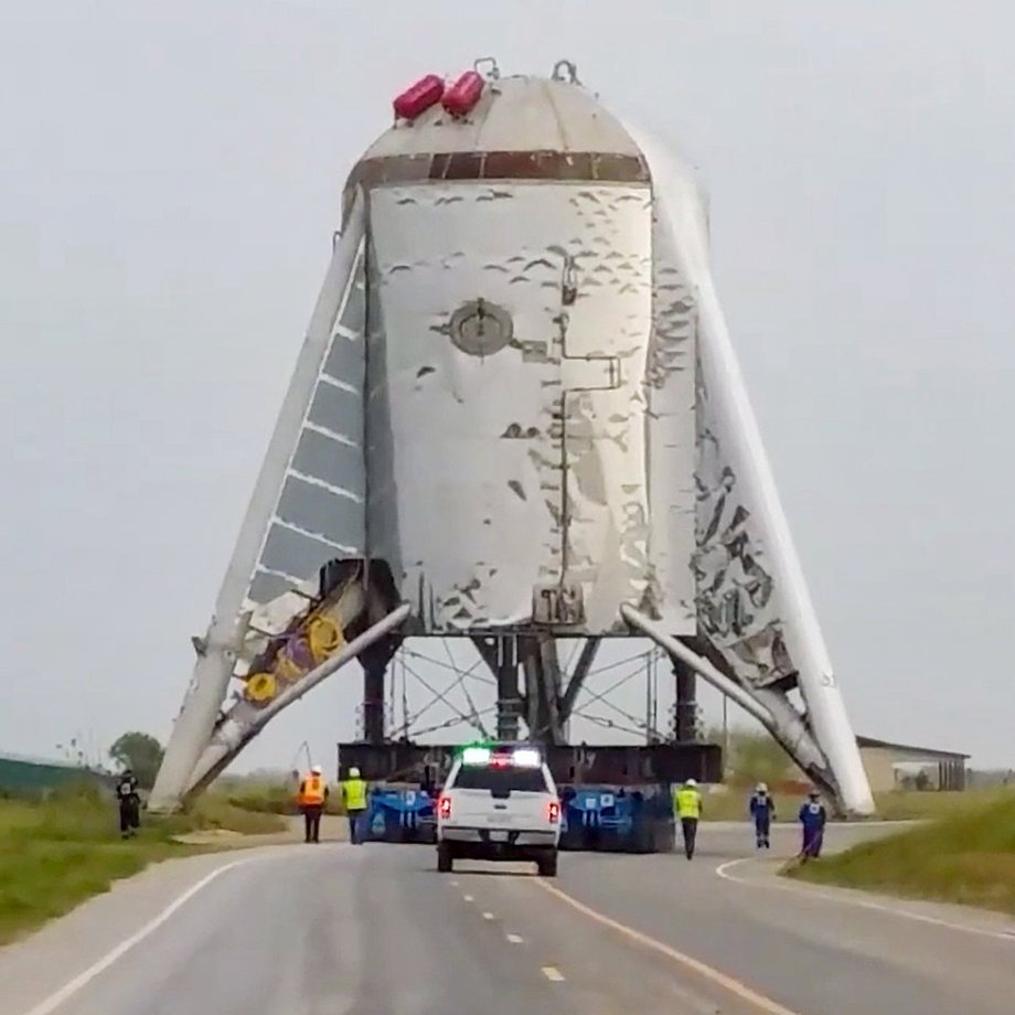 Pracownicy SpaceX i dolna część prototypu Test Hopper w drodze na miejsce startów znajdujące się niedaleko plaży Boca Chica w Teksasie, 8 marca 2019 roku