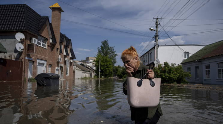 Gátrobbantás miatt vízzel elöntött utcán megy egy nő Herszonban / Fotó: MTI/AP/Jevhen Maloletka